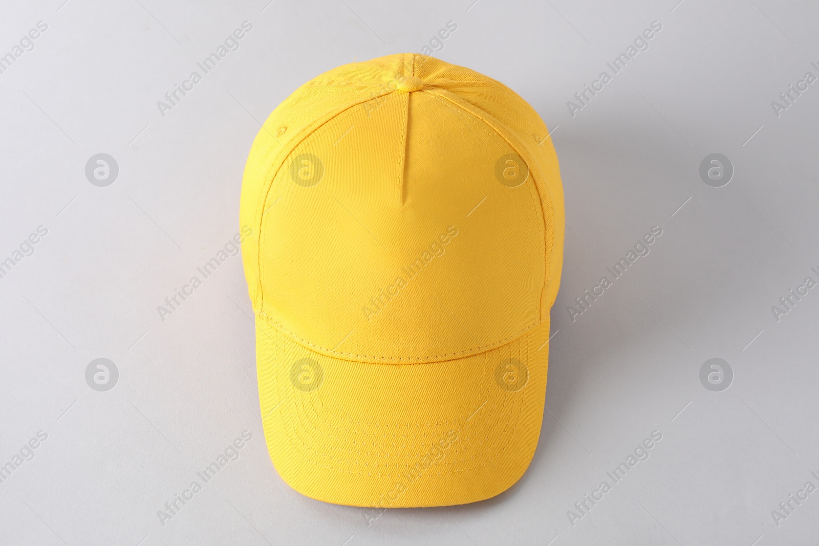 Photo of Stylish yellow baseball cap on light grey background, above view. Mockup for design