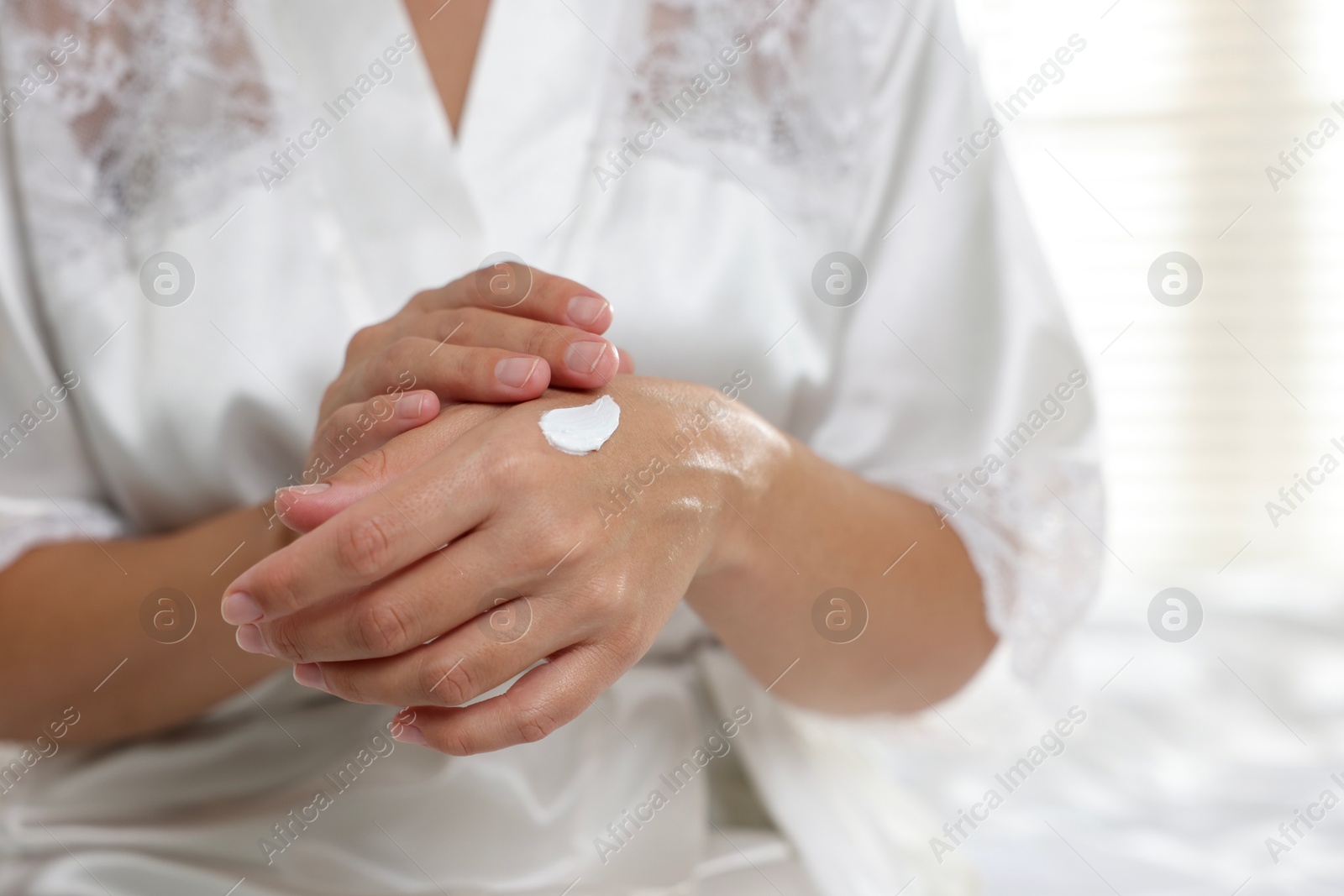 Photo of Woman applying cream onto hand at home, closeup