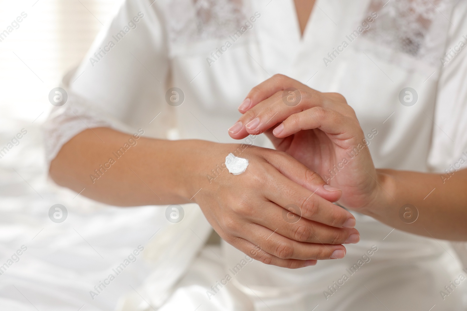 Photo of Woman applying cream onto hand at home, closeup