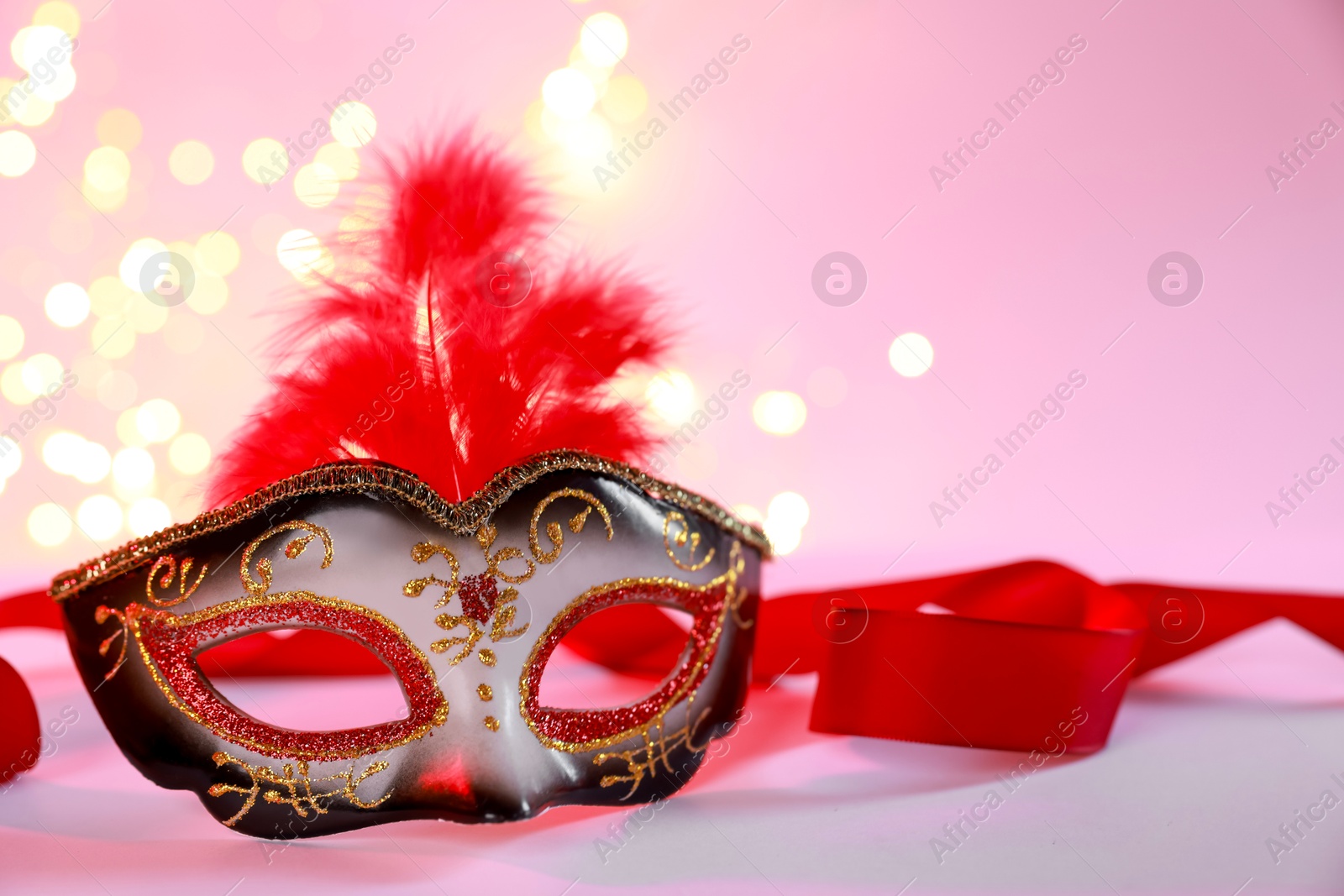 Photo of Beautiful carnival mask on color background, closeup. Bokeh effect