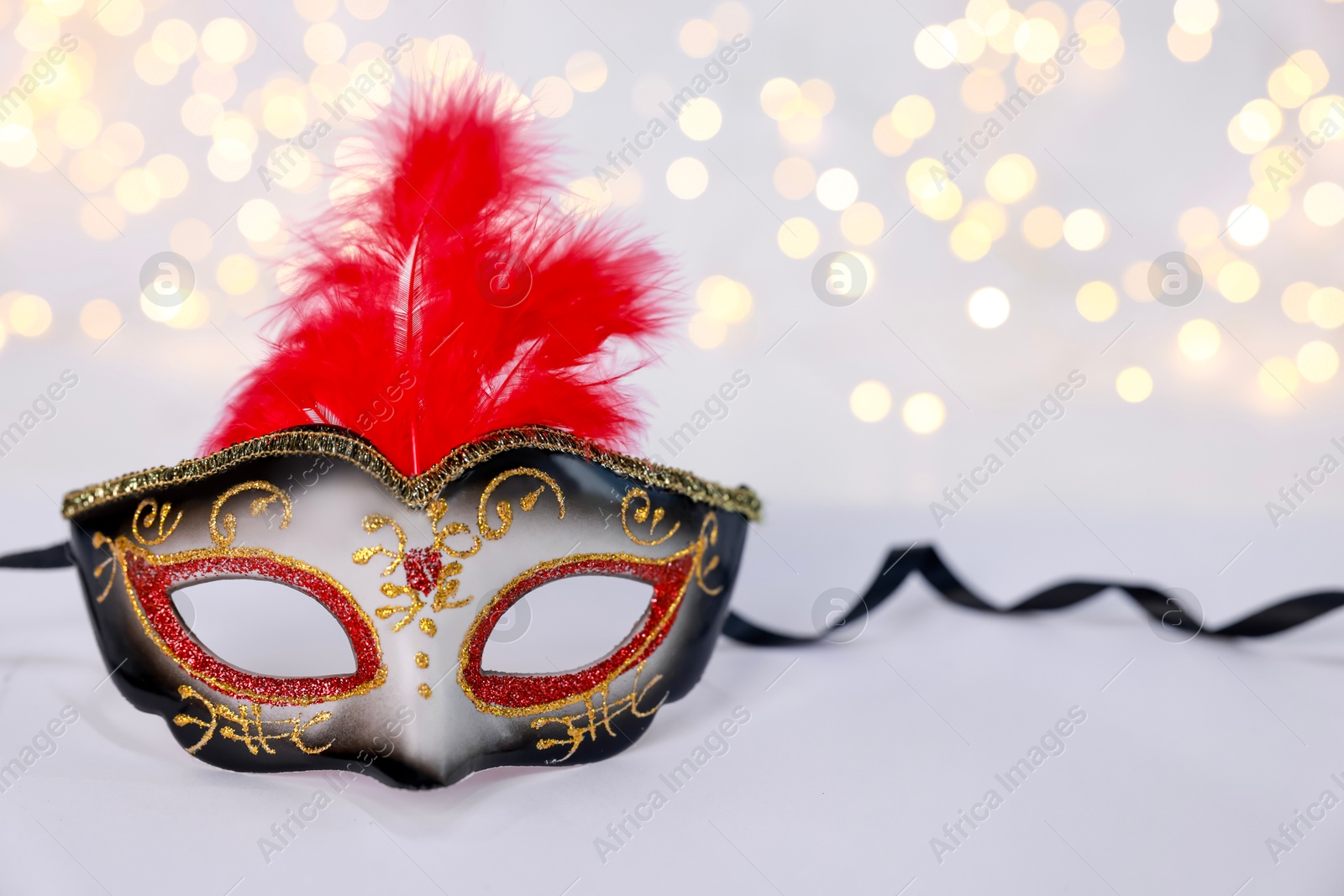 Photo of Beautiful carnival mask on color background, bokeh effect. Space for text