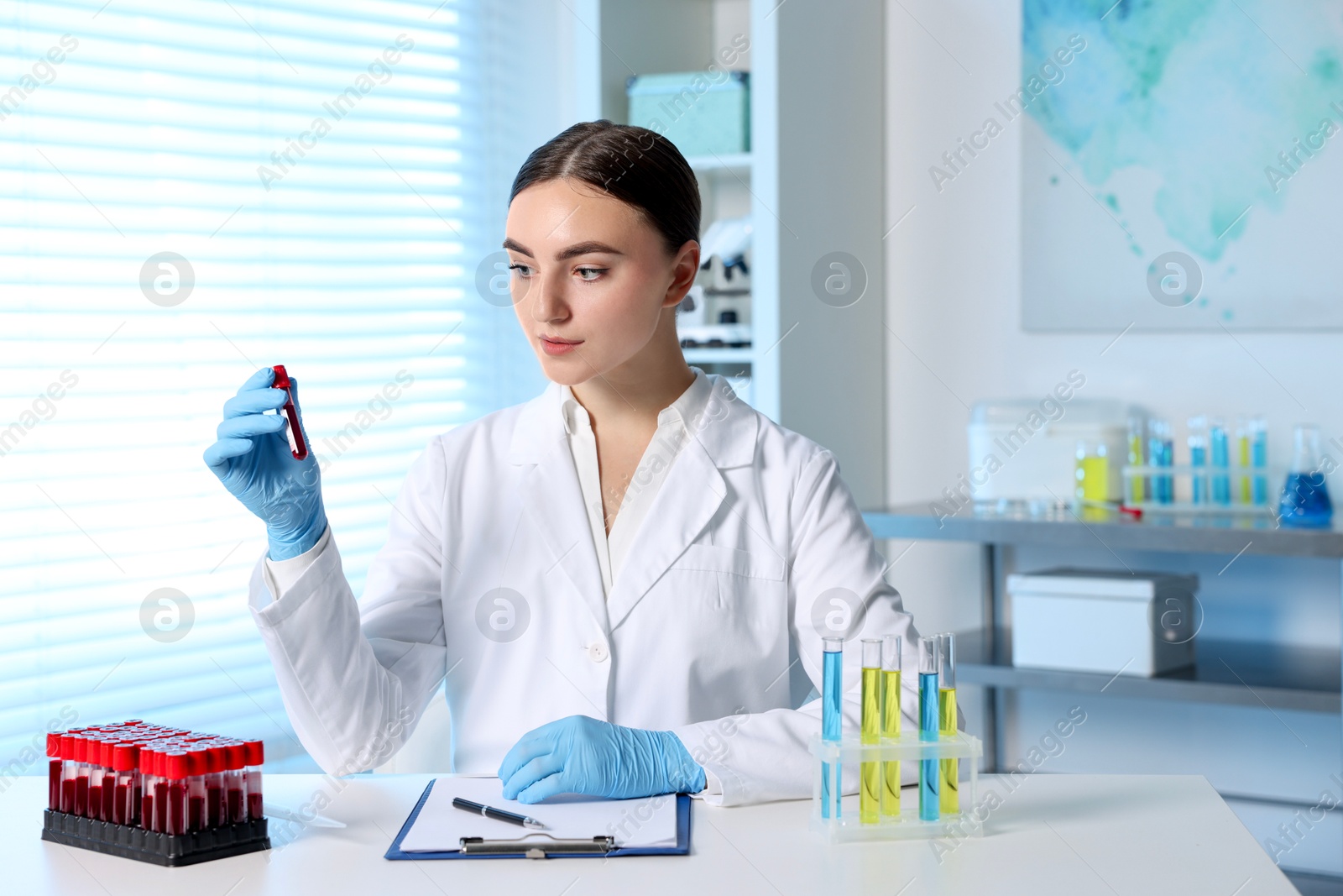 Photo of Laboratory testing. Doctor holding test tube with blood sample at table indoors