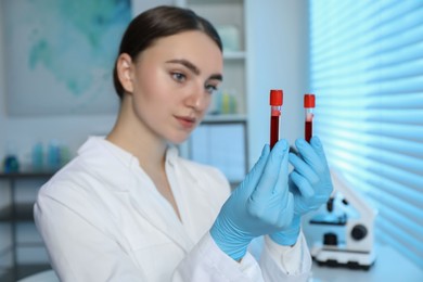 Laboratory testing. Doctor holding test tubes with blood samples indoors