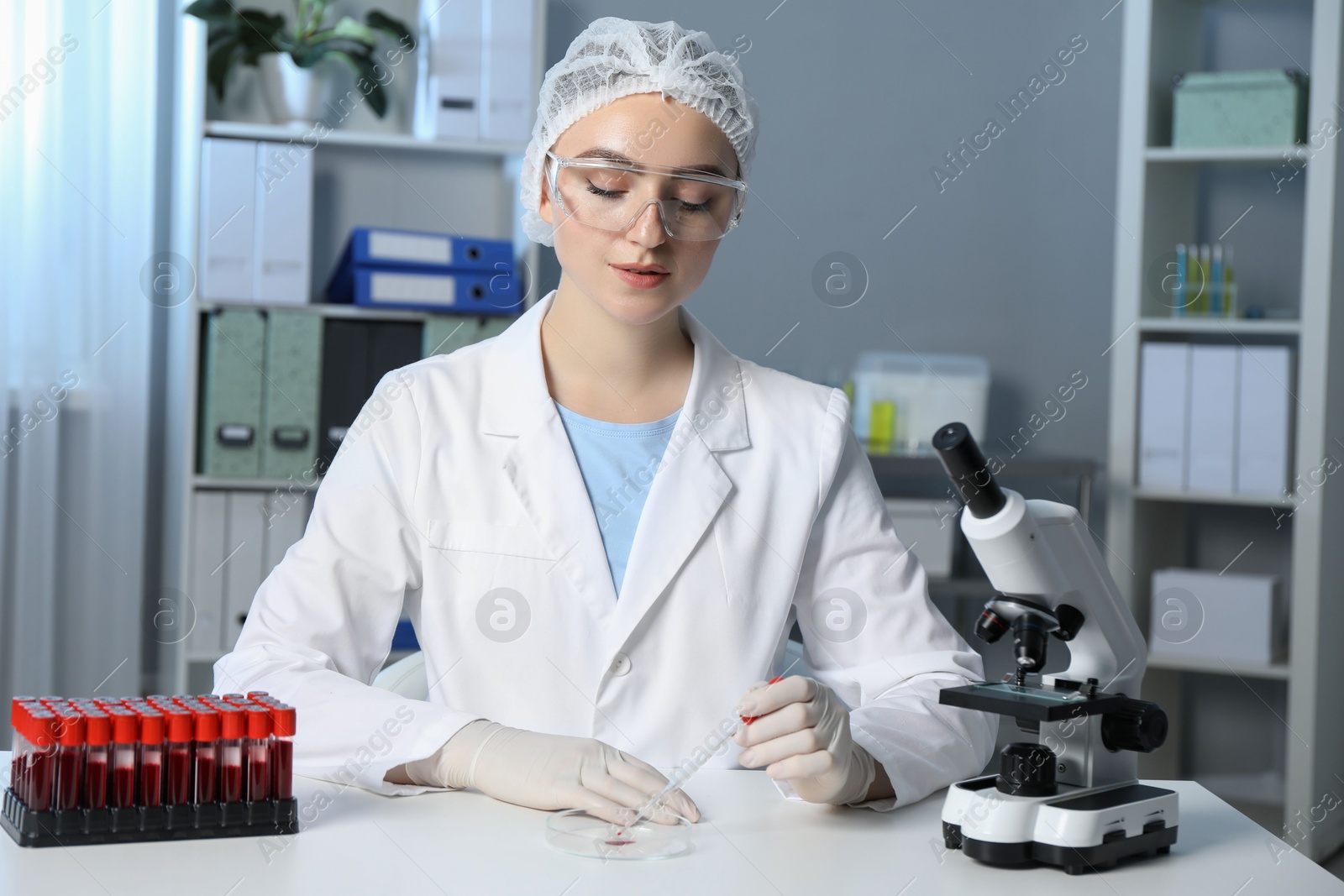 Photo of Laboratory testing. Doctor dripping blood sample into Petri dish at table indoors