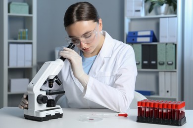 Laboratory testing. Doctor working with microscope at table indoors