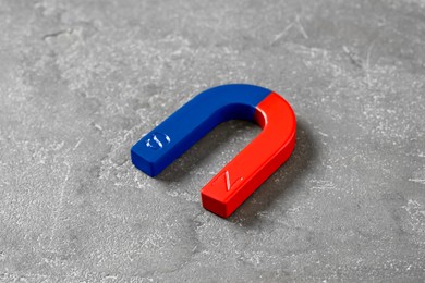 Photo of One horseshoe magnet on grey textured table, closeup