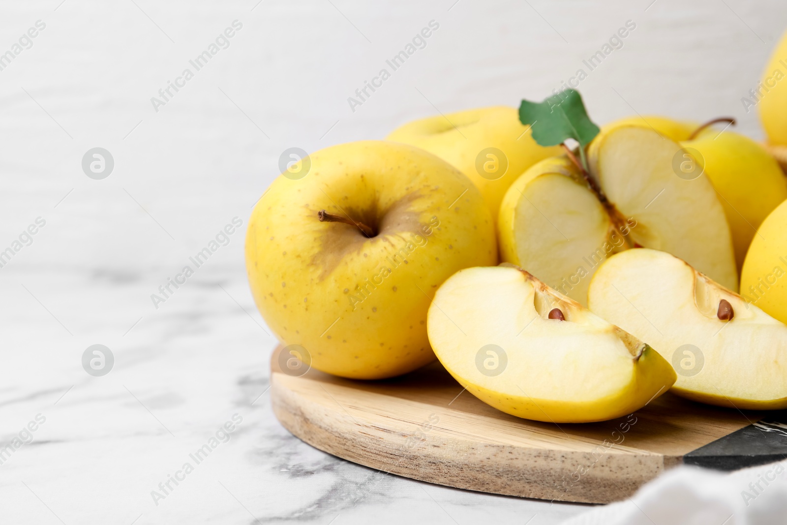 Photo of Ripe yellow apples on white marble table, closeup