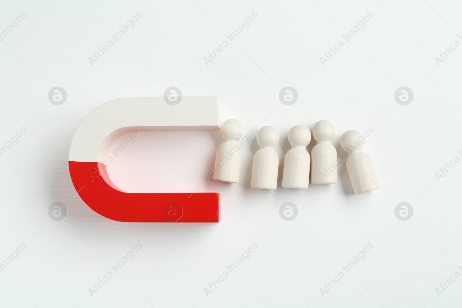 Photo of Magnet attracting wooden human figures on white background, flat lay