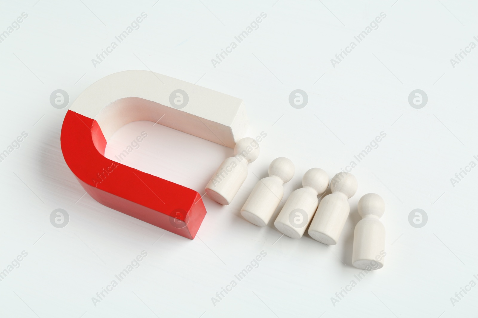 Photo of Magnet attracting wooden human figures on white background