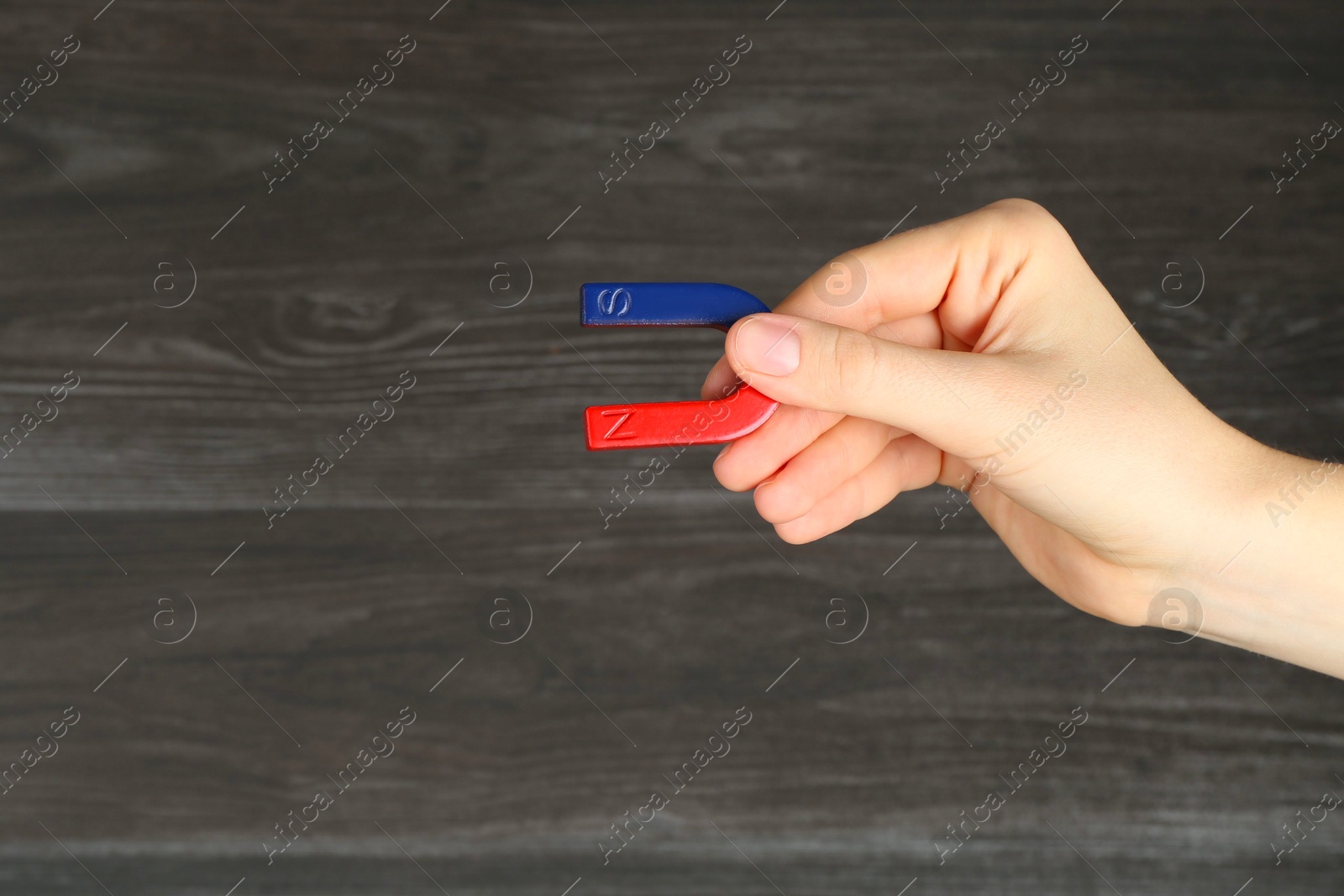 Photo of Woman with horseshoe magnet on wooden background, closeup. Space for text