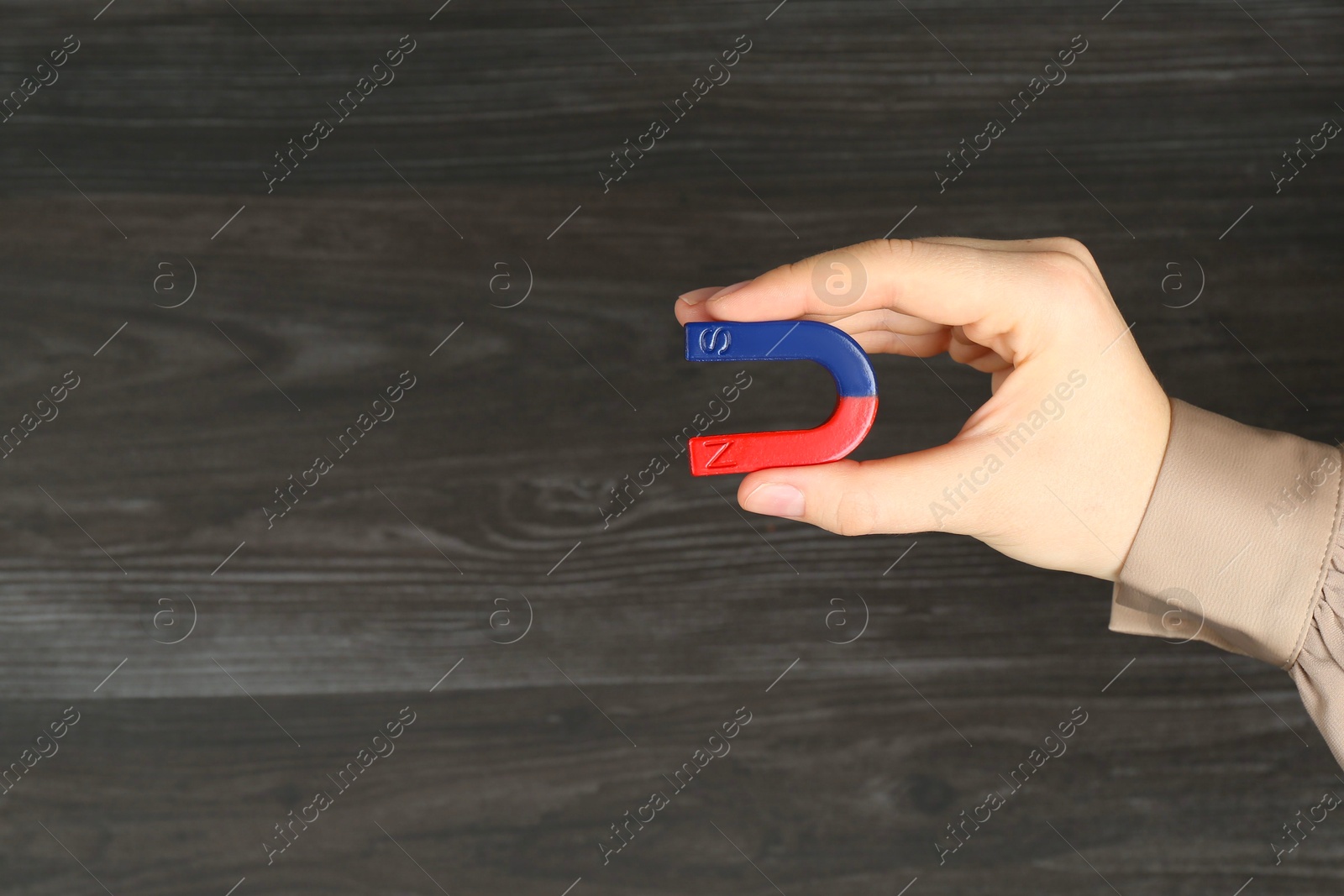 Photo of Woman with horseshoe magnet on wooden background, closeup. Space for text