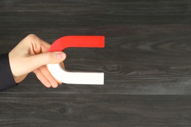 Photo of Woman with horseshoe magnet on wooden background, closeup. Space for text