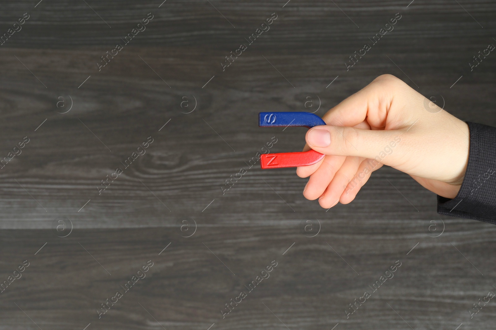 Photo of Woman with horseshoe magnet on wooden background, closeup. Space for text