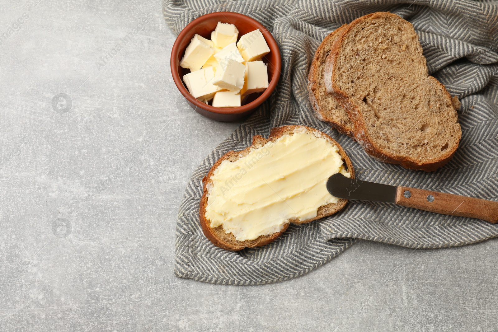Fresh bread with butter and knife on grey table, flat lay. Space for text Photo of Fresh bread with butter and knife on grey table, flat lay. Space for text