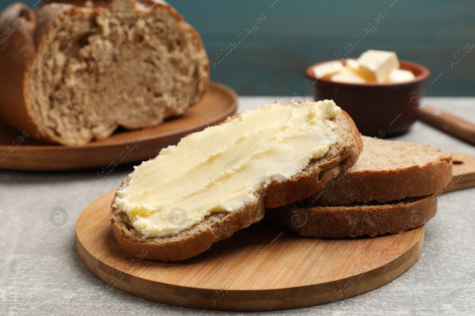 Photo of Fresh bread with butter on grey table, closeup