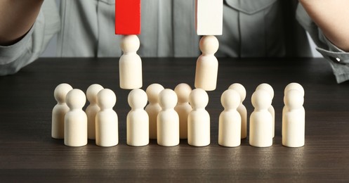 Photo of Attracting human figures with magnet at wooden table, closeup