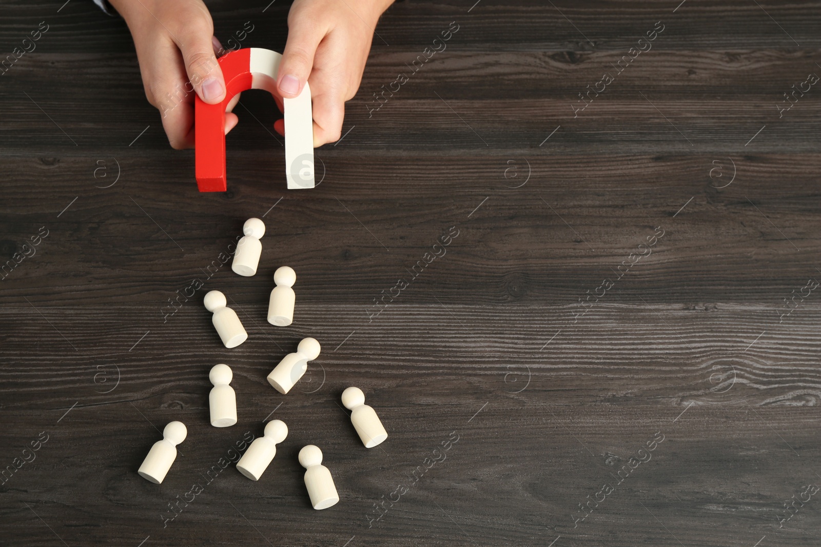 Photo of Man with magnet attracting human figures at wooden table, above view. Space for text