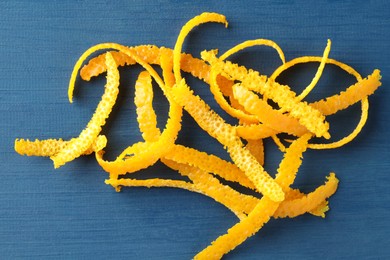 Photo of Pile of fresh orange zest on blue wooden table, top view