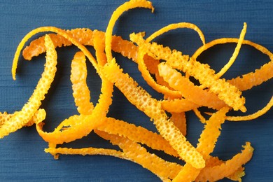 Photo of Pile of fresh orange zest on blue wooden table, top view