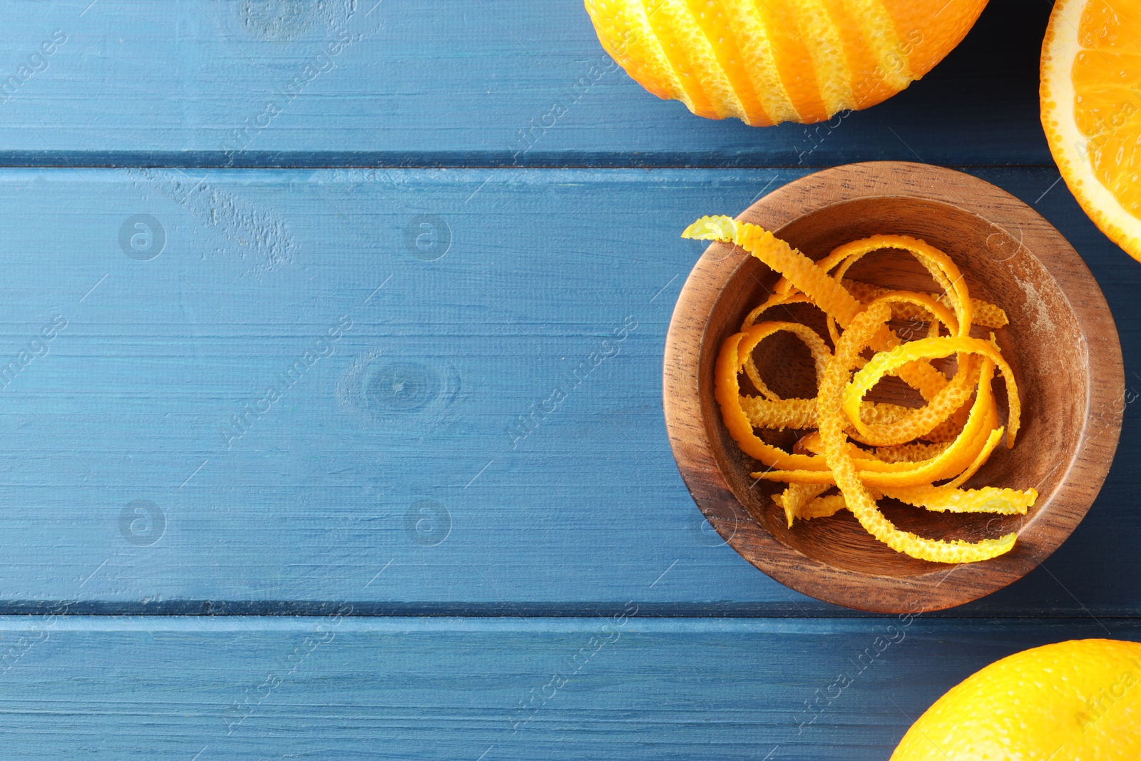 Photo of Bowl with fresh orange zest and fruits on blue wooden table, flat lay. Space for text