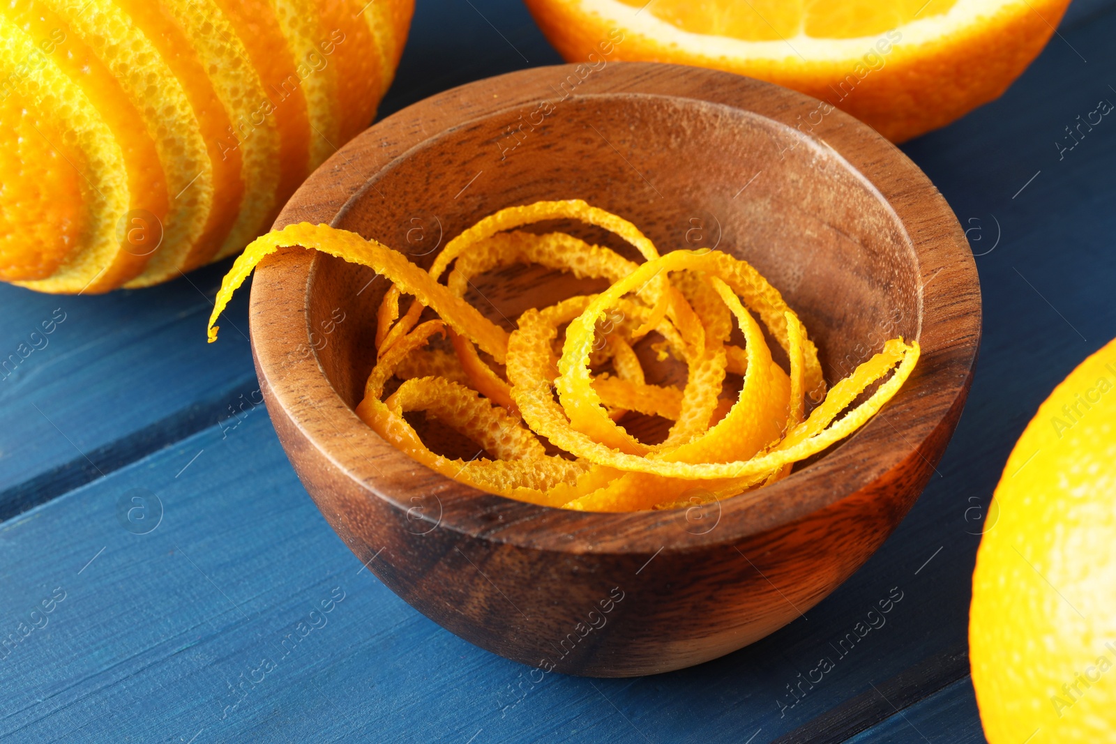 Photo of Bowl with fresh orange zest and fruits on blue wooden table, closeup