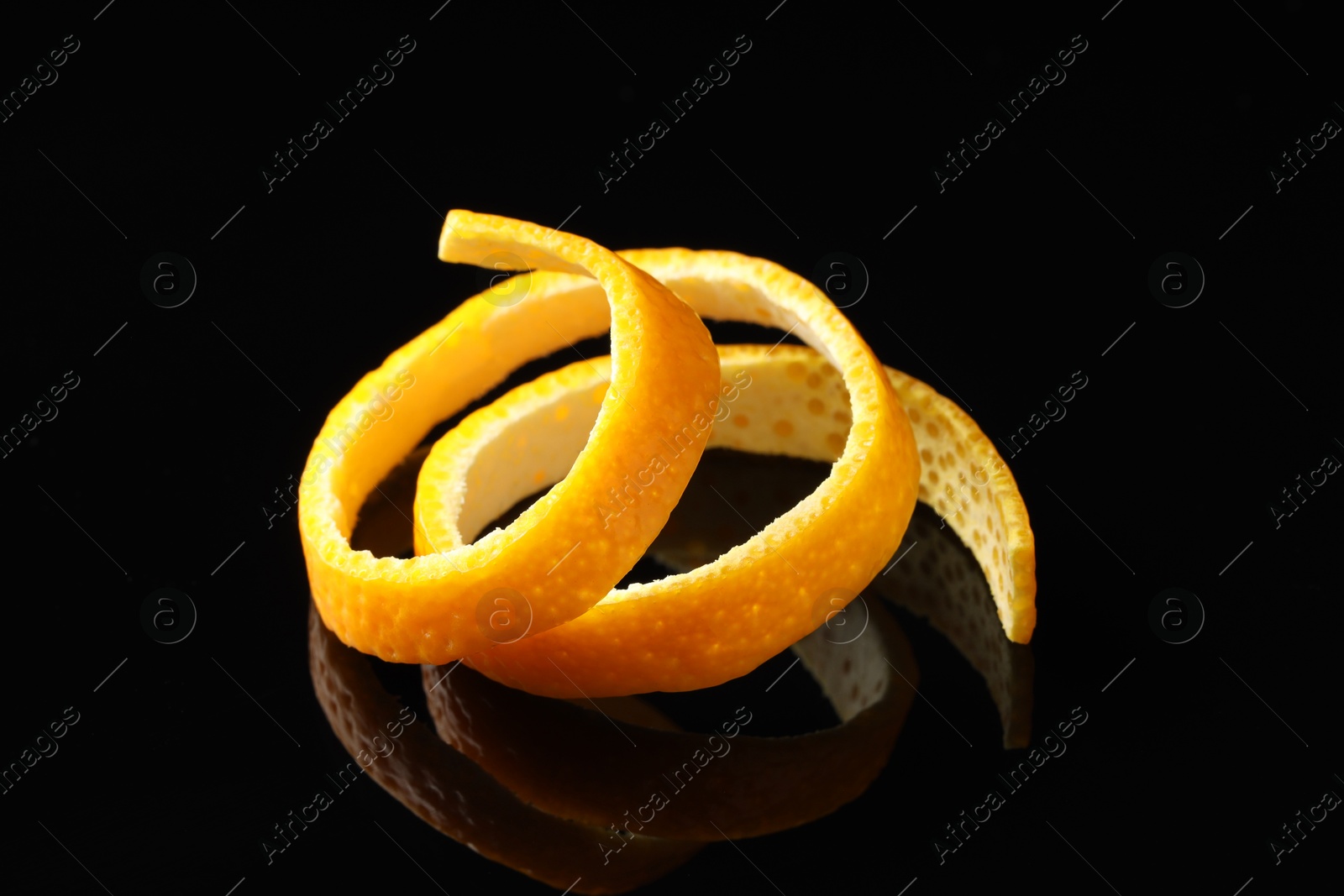 Photo of One fresh orange peel on black mirror surface, closeup