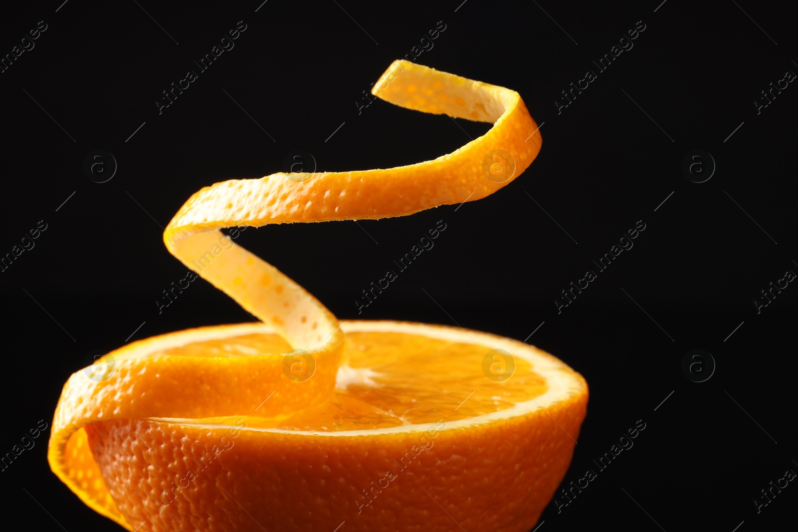 Photo of Fresh orange peel and half of fruit on black background, closeup