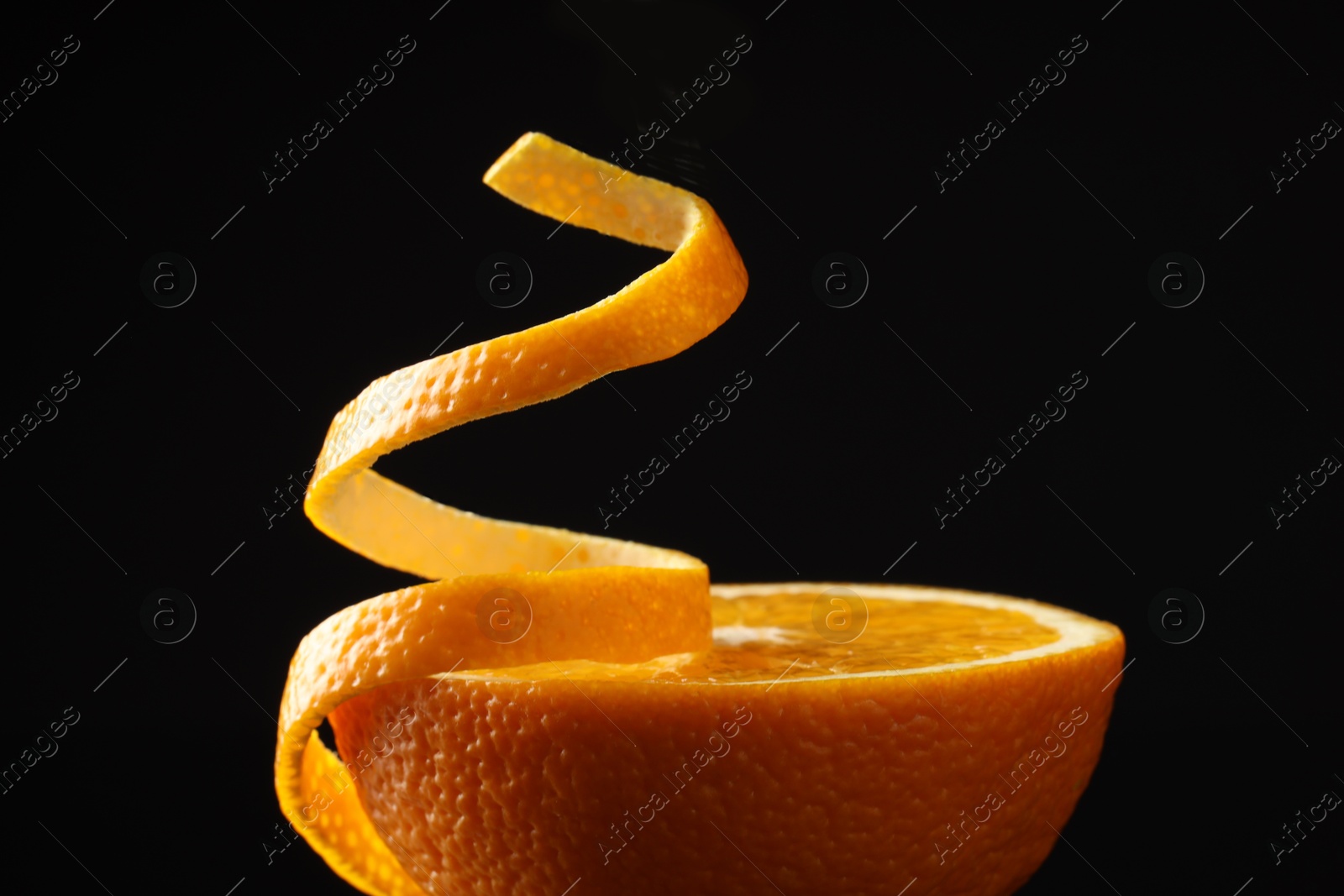 Photo of Fresh orange peel and half of fruit on black background, closeup