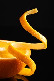 Photo of Fresh orange peel and half of fruit on black background, closeup