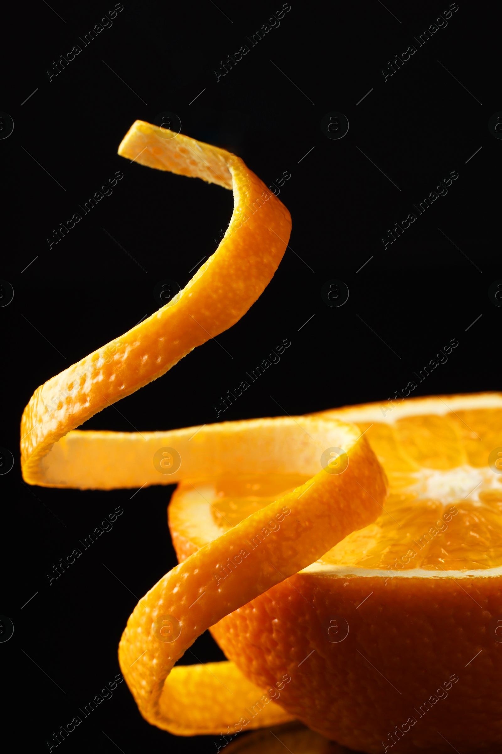 Photo of Fresh orange peel and half of fruit on black background, closeup