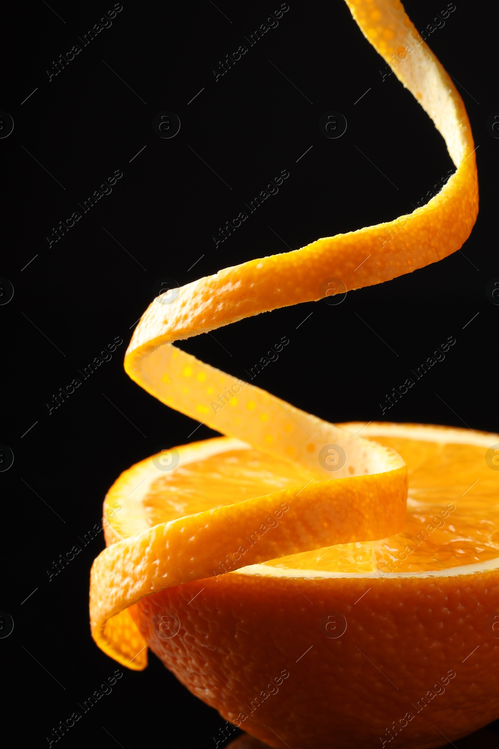 Photo of Fresh orange peel and half of fruit on black background, closeup