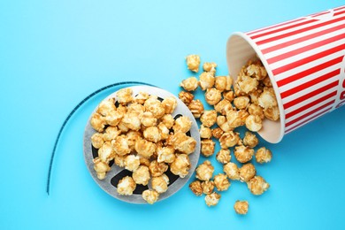 Photo of Sweet popcorn and film reel on light blue background, top view. Watching movie