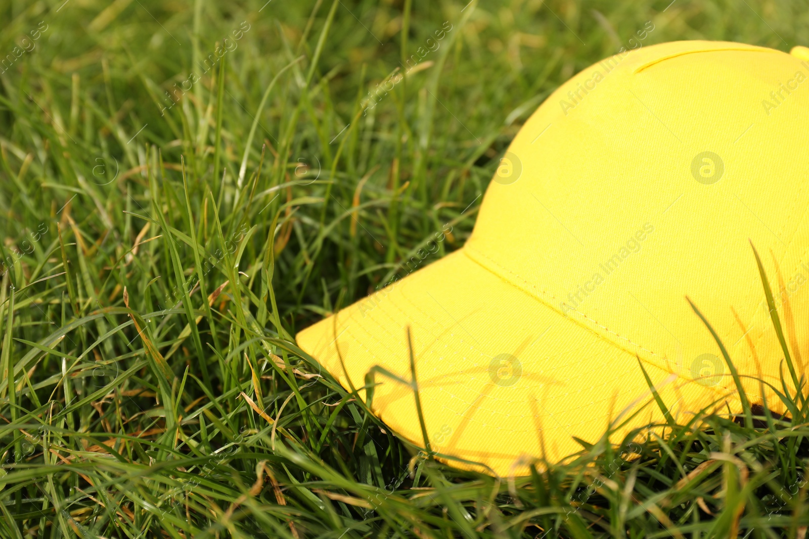 Photo of Stylish baseball cap on green grass, closeup. Mockup for design