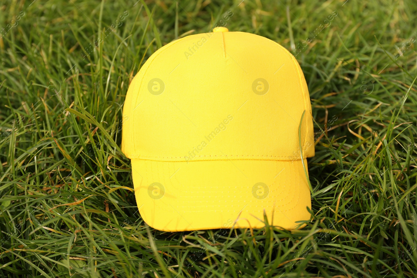 Photo of Stylish baseball cap on green grass, closeup. Mockup for design