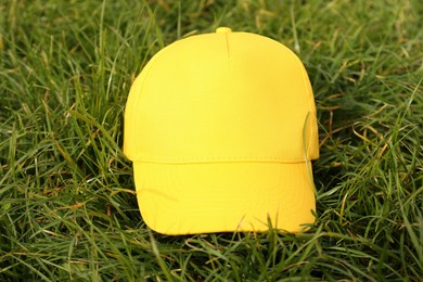 Photo of Stylish baseball cap on green grass, closeup. Mockup for design