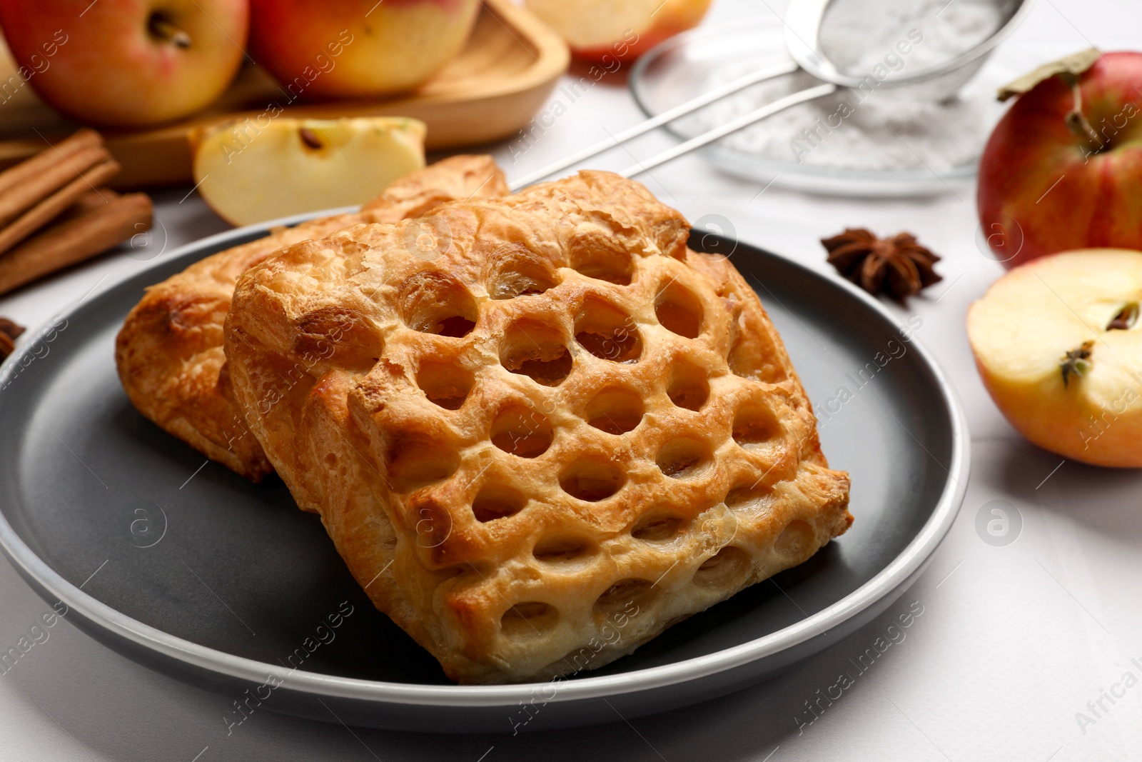 Photo of Delicious puff pastries and apples on white table, closeup