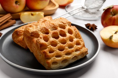 Photo of Delicious puff pastries and apples on white table, closeup