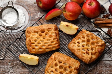 Delicious puff pastries with fruit filling and apples on wooden table, top view