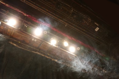 Photo of Professional spotlights and smoke on stage in theatre, low angle view