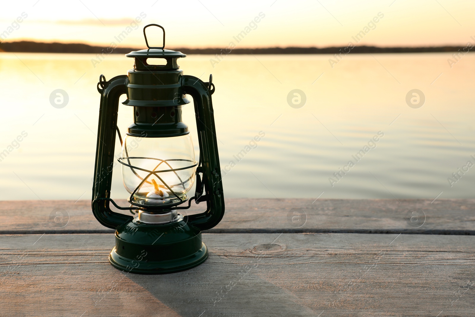 Photo of Vintage kerosene lamp on wooden surface in evening. Space for text