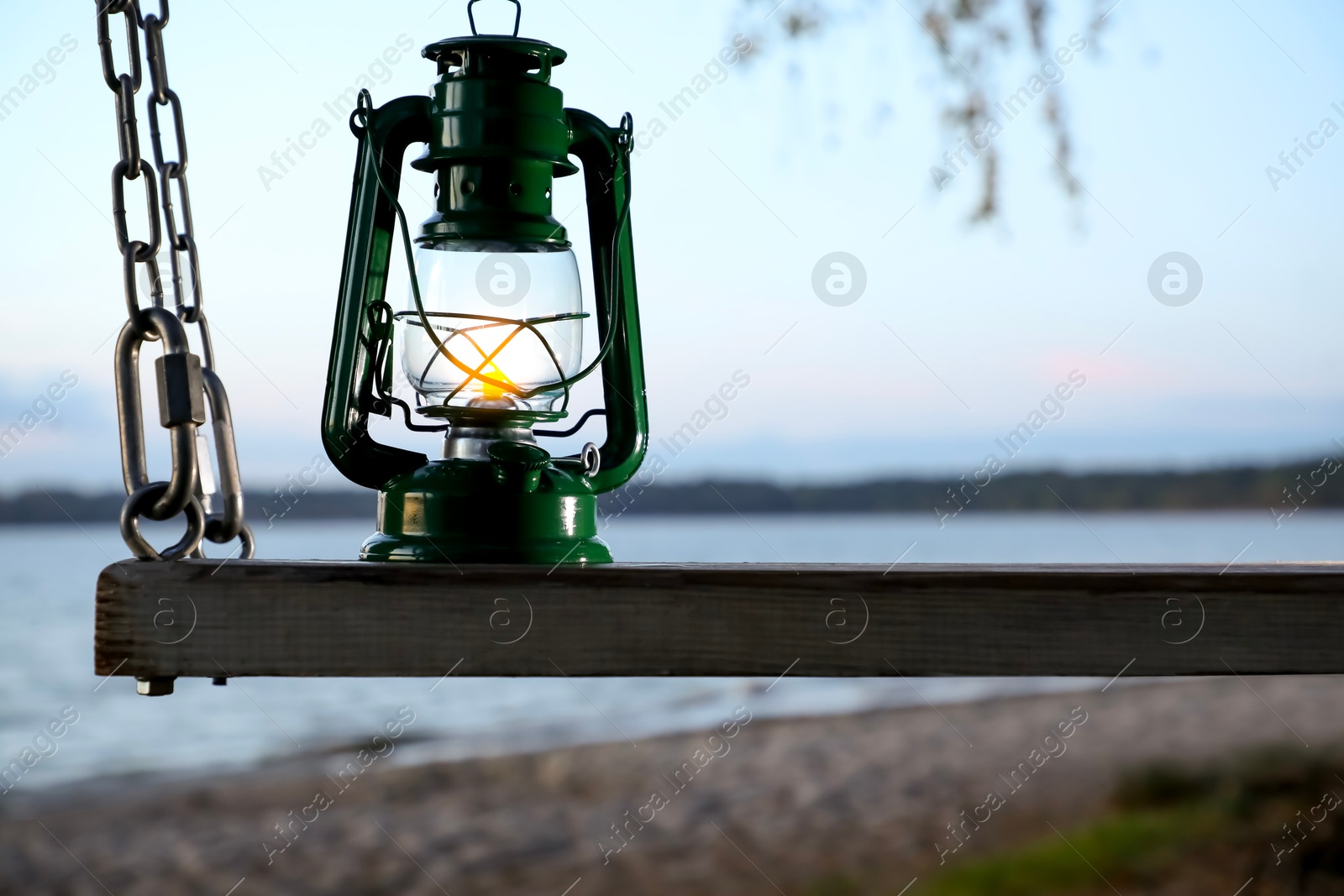 Photo of Vintage kerosene lamp on swing at beach in evening