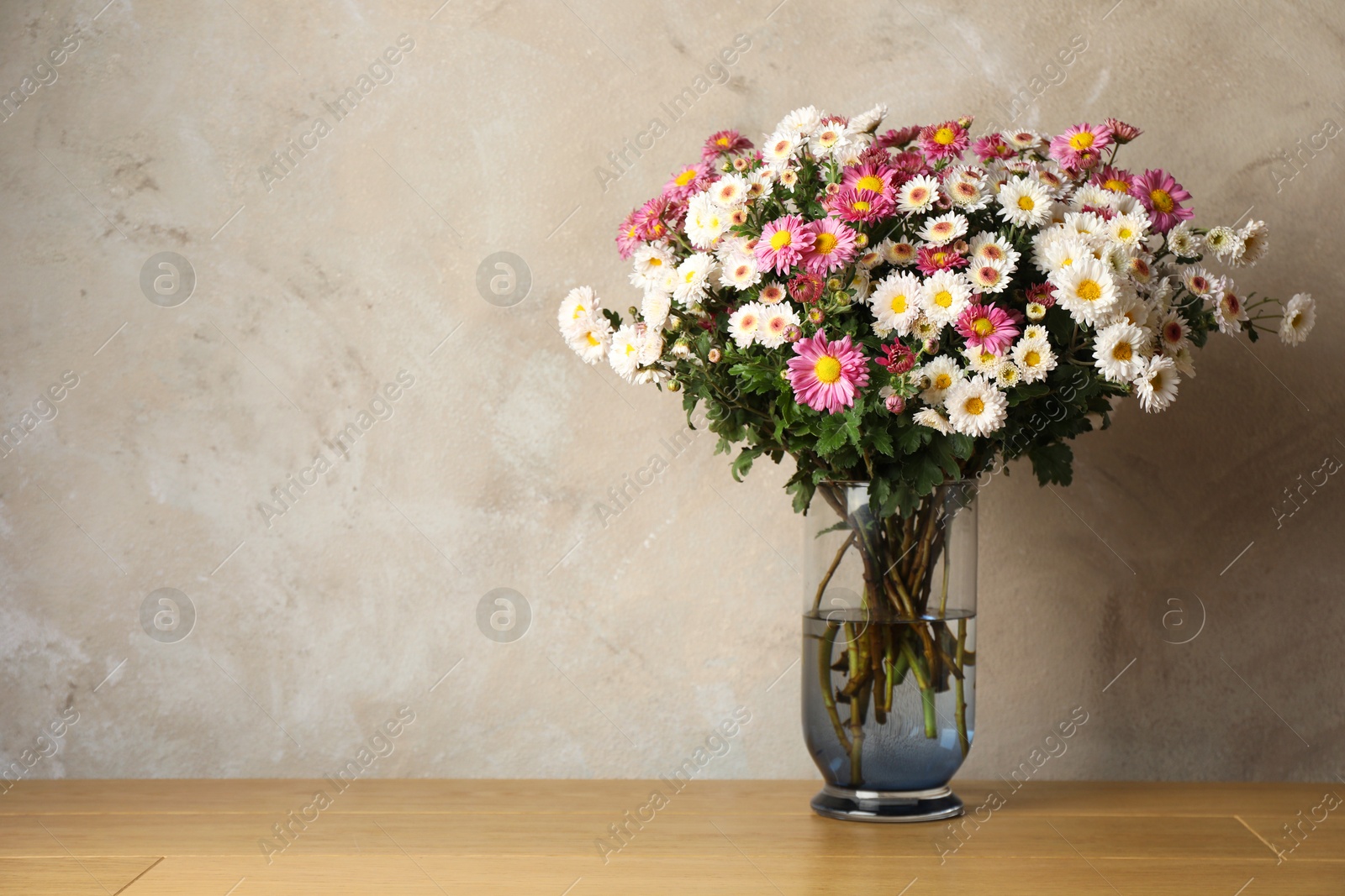 Photo of Vase with beautiful flowers on pink wooden table, space for text