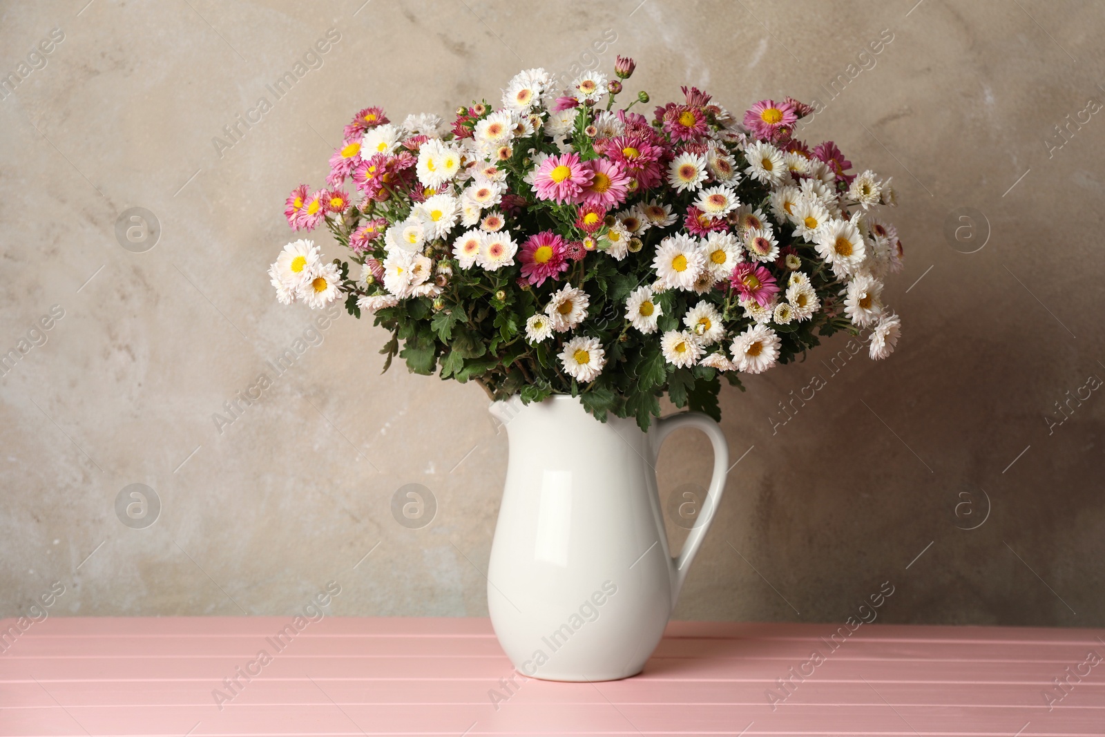 Photo of Vase with beautiful flowers on pink wooden table