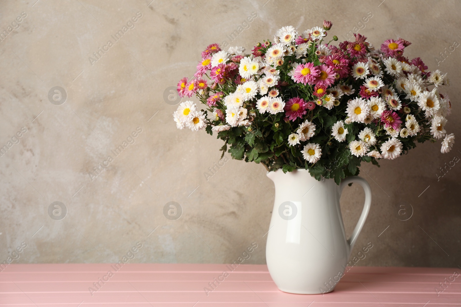 Photo of Vase with beautiful flowers on pink wooden table, space for text