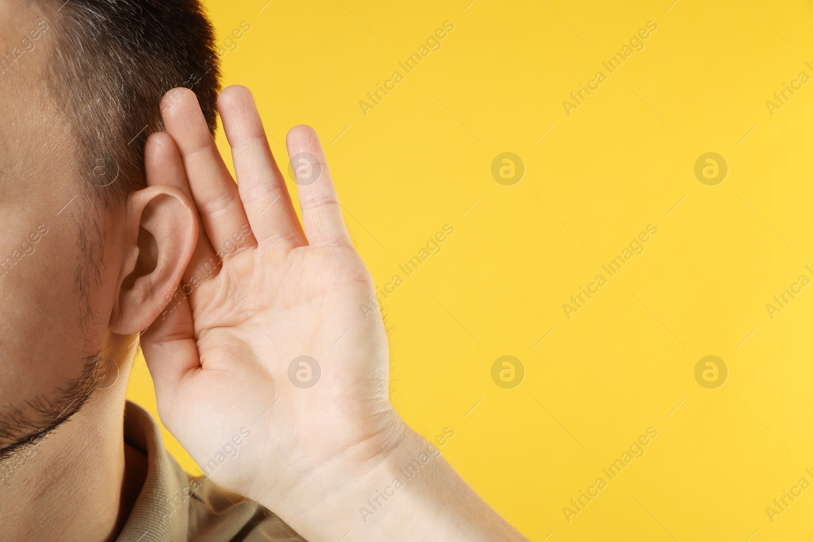 Photo of Man showing hand to ear gesture on orange background, closeup. Space for text