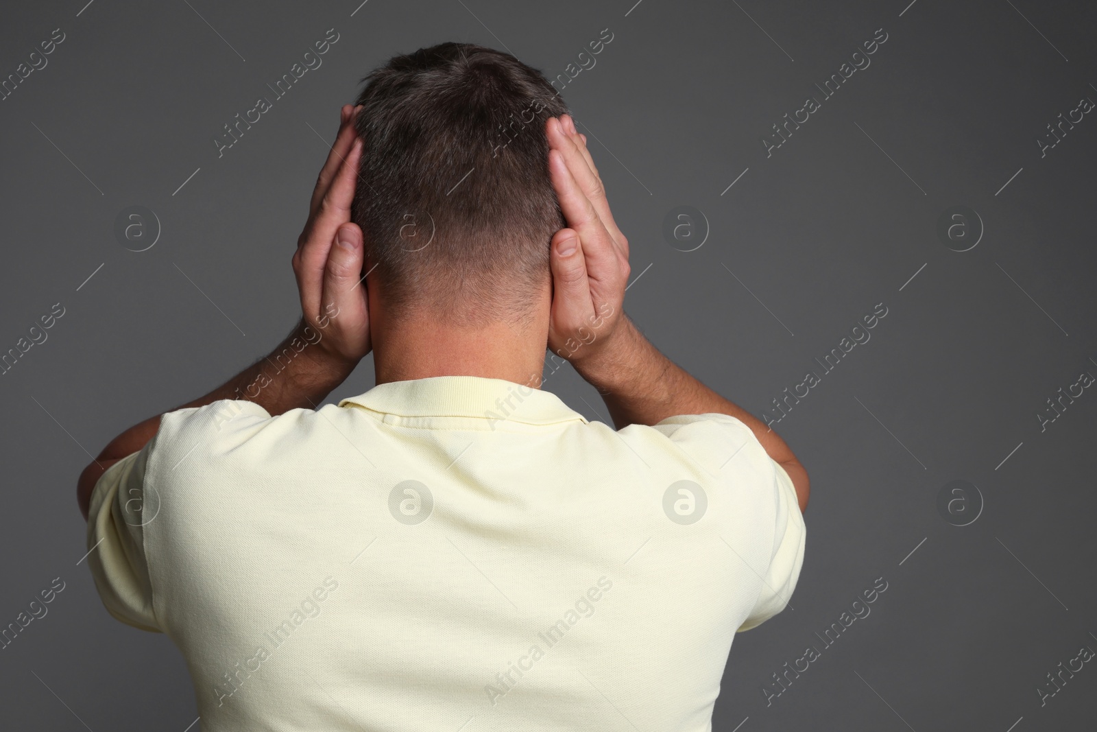 Photo of Man covering his ears on grey background, back view