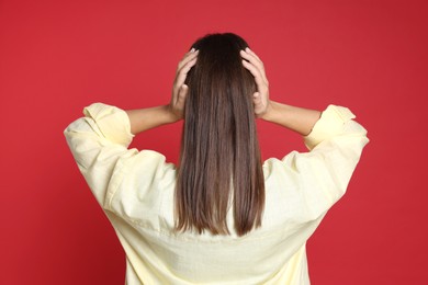 Photo of Woman covering her ears on red background, back view