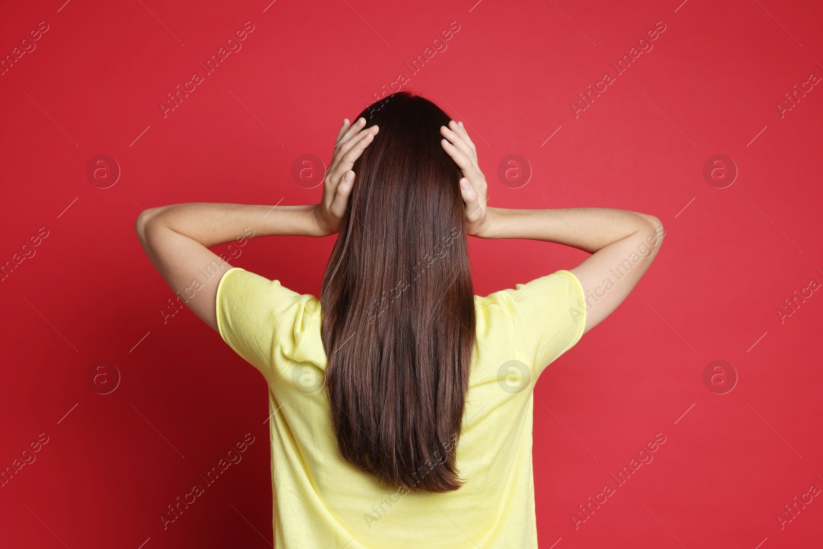 Photo of Woman covering her ears on red background, back view