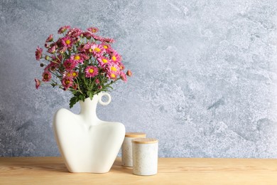 Photo of Stylish vase with beautiful flowers on wooden table. Space for text