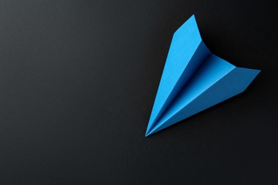 Photo of One handmade light blue paper plane on black background, top view. Space for text